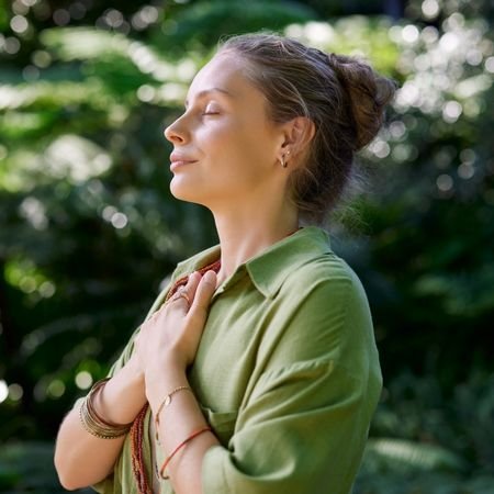 woman in a green button shirt with her hands on her chest and eyes closed, taking in the moment. | When Empaths Integrate | Laura Rowe | The Vital Spirit | Emapth Mentor