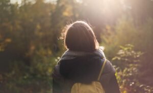 Woman walking through nature in fall wearing a blue hoodie under a gray fall jacket with a backpack | Your Empath Journey | The Vital Spirit | Laura Rowe | Empath Mentor